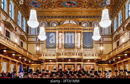 Eine Pfeifenorgel, Kristallkronleuchter und vergoldete Karyatiden umrahmen die Orchesterbühne mit Musikständern im Großer Musikvereinssaal. Stockfoto