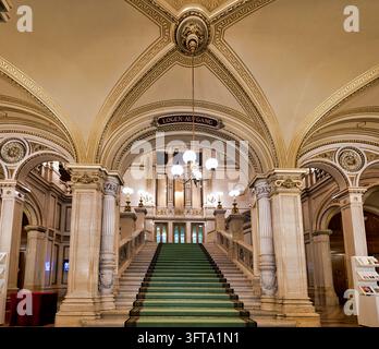 Grünteppich-belegte Marmortreppe unter einer vergoldeten gewölbten Decke der Wiener Staatsoper, die zum Logen-Aufgang-Eingang führt. Stockfoto