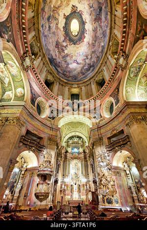 Barocke Schiff der Peterskirche in Österreichs Hauptstadt, mit Rottmayrs Deckenmalerei, vergoldeter Kanzel und Hochaltar, gesehen von den Kirchenbänken Stockfoto