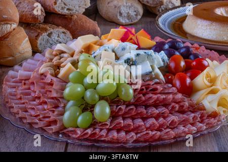 Ein reichhaltiges und appetitliches Charcuterie-Platte gefüllt mit dünn geschnittenem Salami, Schinken, gerolltem Käse, Blauschimmelkäse, Cheddar-Würfeln, Cashewnüssen, grünen Trauben, bla Stockfoto
