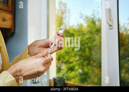 Person vorbereitet sich zur Selbstinjektion von Insulin in der Küche. Hände halten Spritze und Fläschchen, Nahaufnahme Stockfoto