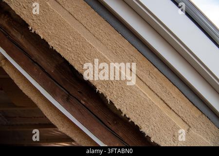 Ansicht von sparender Isolierung, freiliegenden dunklen Holzträgern und neu eingebautem Dachfenster, Dachboden wird isoliert, Renovierung eines alten Gebäudes, Stuttgart, Baden-Wue Stockfoto