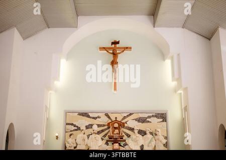 Jesus-Christus-Kruzifix und Reliefwand im Inneren einer katholischen Kirche Stockfoto