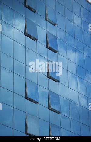 Gebäude mit Glasfassade, die Wolken am Himmel reflektiert Stockfoto