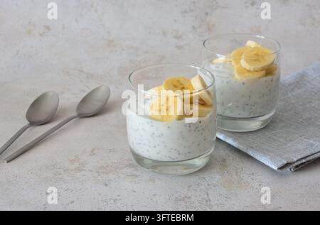 Chia-Pudding mit Bananenscheiben, serviert in Gläsern auf der Tischplatte Stockfoto