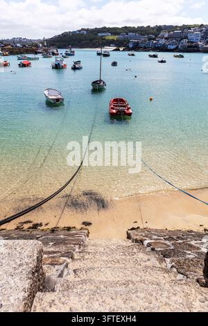 St Ives, Cornwall, UK. Traditionelle Fischer- und Freizeitboote liegen in den ruhigen Gewässern des St Ives Harbour vor Anker mit der Hafenmauer, Leuchtturm Stockfoto
