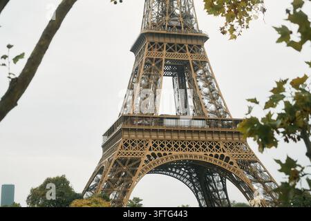 Eiffelturm Unterteil Eisengitter und Aussichtsplattform eingerahmt von Herbstbäumen in Paris, Nahaufnahme zeigt Bögen, Balken und Treppen von Stockfoto