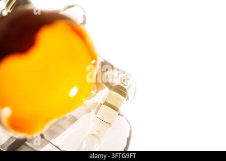 Transluzentes Glasornament zeigt lebhafte orange und gelbe Formen neben reflektierenden gekrümmten Oberflächen vor einem hellen weißen Hintergrund mit sanftem Lichtreflex Stockfoto