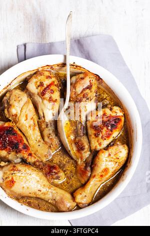 Ofengebratenes Hühnerdrumsticks, mariniert in Sojasauce, Balsamico-Essig, Vollkornsenf, Honig, Olivenöl und getrockneten Kräutern, serviert in einer weißen Keramikschale Stockfoto
