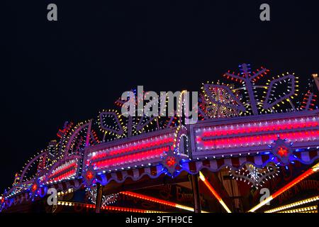 Ein festliches Karussell oder Vergnügungsfahrzeug, das mit leuchtenden Lichtern im Hyde Park Winter Wonderland in London geschmückt ist. Stockfoto