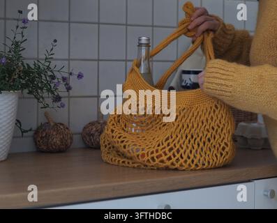 Frau hält gelbe Häkel-Einkaufstasche aus wiederverwendbarem Material, umweltfreundliche Alternative zu Plastiktüten Stockfoto