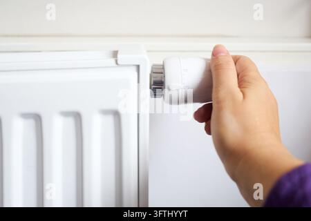 Hand, die den Heizungs-Thermostatventilregler für die Hausheizung einstellt Stockfoto