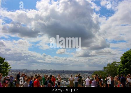 Paris, Frankreich – 31. Juli 2019: Blick auf die Stadtlandschaft von Paris aus Montmartre mit einer großen Wolkenformation am blauen Himmel und einer Menschenmenge, die genießt Stockfoto
