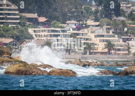 Ozeanwellen schlagen an die felsige Küste mit Küstenhäusern in Algarrobo, Chile. Stockfoto