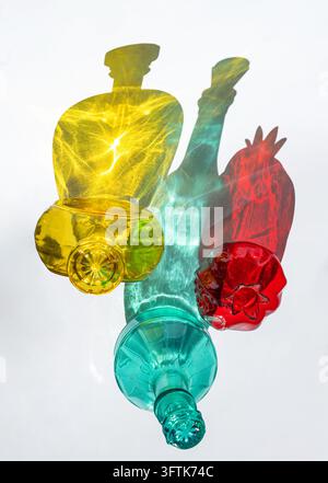 Bunte Glasflaschen werfen lebendige Schatten auf Weiß Stockfoto