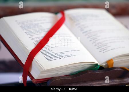 Ein offenes liturgisches Missale mit lateinischen Texten ruht auf einem lackierten Holzlectern. Stockfoto