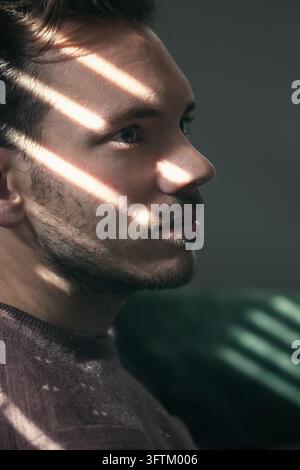 Porträt eines kaukasischen Mannes im Schatten der Jalousien Stockfoto