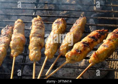 Spieße mit Hackfleisch garen auf dem Grill über glühenden Kohlen. Stockfoto