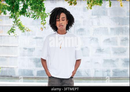 Junger Mann mit Dreadlocks trägt ein übergroßes T-Shirt und steht im Freien Stockfoto