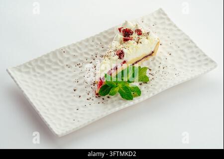 Elegante Scheibe Cranberryscheesecake mit Minz-Garnitur auf einem Teller Stockfoto