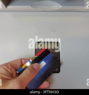Hand, die Kreditkarten in der Nähe eines Kartenlesers für die Zahlung hält Stockfoto