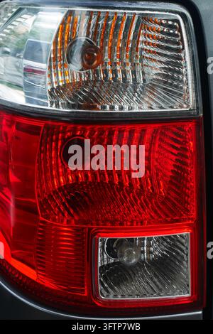 Nahaufnahme einer modernen Heckleuchte mit roten und klaren Kappen, die Bremslicht- und Blinklichtdetails zeigt. Stockfoto