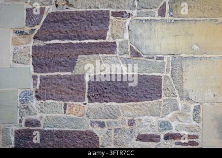 Rustikale mehrfarbige Sandstein-Wandtextur-Hintergrund mit unregelmäßigen Steinblöcken Stockfoto