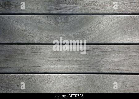 Verwitterte graue Bretter verlaufen über das Bild, zeigen Holzmaserung und schmale dunkle Spalten; kein Ort oder Tageszeit ist erkennbar. Stockfoto