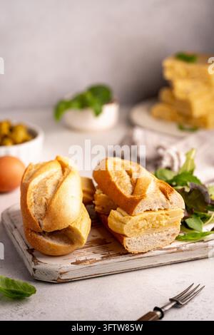 Spanisches Kartoffelomelette-Sandwich. Typisch spanisches Essen, Bocadillo de Tortilla espanola sehr beliebter Snack in Spanien auf weißem rustikalem Hintergrund Stockfoto