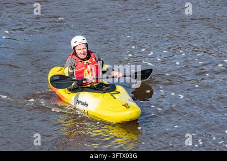 Kayaker paddelt Pyranha-Kajak mit TNP-Paddel auf Flusswasser und trägt Helm und Schwimmweste Stockfoto