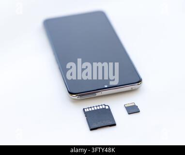 Ein modernes Smartphone ruht auf einer weißen Oberfläche mit Speicherkarten Stockfoto