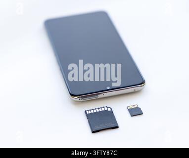 Ein modernes Smartphone ruht auf einer weißen Oberfläche mit Speicherkarten Stockfoto