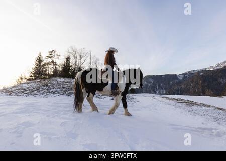 Reiterin entspannt sich zu Pferd in friedlicher Winternatur, verbindet sich mit ihrem Pferd und genießt den Reiterlebensstil. Stockfoto