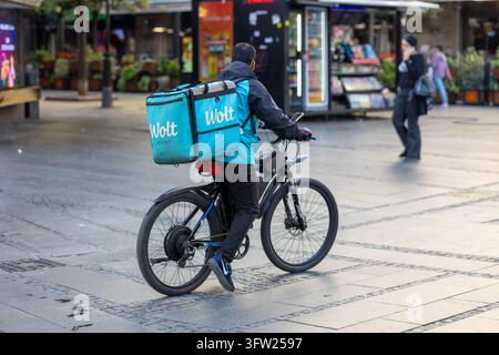BELGRAD, SERBIEN - 29. SEPTEMBER 2026: Ein Wolt-Lieferkurier mit einer großen markierten Liefertasche sitzt auf einem Elektrofahrrad und überprüft die Navigation Stockfoto