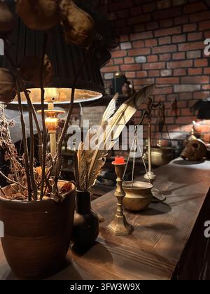Vintage-Stillleben mit Messingwaage, Federkiel, Kerze und Totenkopf auf einem Holztisch. Stockfoto
