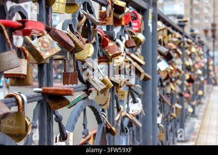 Viele Liebesschlösser, die an einem Metallgeländer auf einer Brücke in der Stadt befestigt sind. Stockfoto