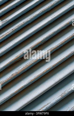 Nahaufnahme, die abblätternde Farbe auf verwitterten blauen Holzlamellen zeigt. Texturierte Oberfläche, die Verfall und abgenutzte Details offenbart Stockfoto