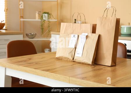 Lieferung von Lebensmitteln und Einkauf von Lebensmitteln, Papiertüten mit Quittungen auf einem Küchentisch, die den Heimessenservice und Bequemlichkeit im modernen Lebensstil darstellen Stockfoto