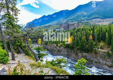 Atemberaubender Herbstblick auf das historische Fairmont Banff Springs Hotel, das in der Kiefernwaldung über den Bow Falls und dem Bow River im Banff-Nationalpark eingebettet ist Stockfoto