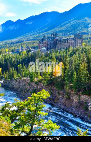 Atemberaubender Herbstblick auf das historische Fairmont Banff Springs Hotel, das in der Kiefernwaldung über den Bow Falls und dem Bow River im Banff-Nationalpark eingebettet ist Stockfoto