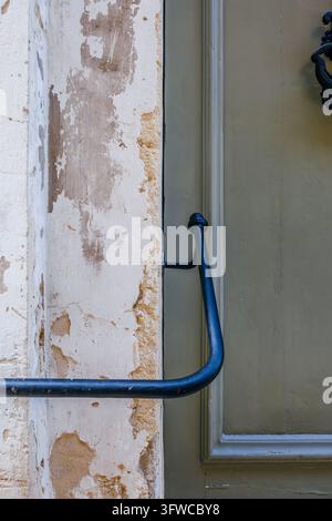 Grüne Holztür und schwarzes Metallgeländer Detail, verwitterte bemalte Paneele, historischer Kalksteinmauertextur, traditionelle Architektur Stockfoto