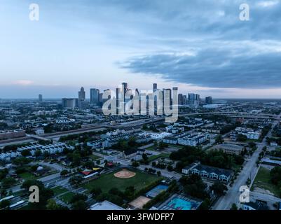 Luftbild, das die Skyline von Houston im Morgengrauen mit kalten Tönen einfängt. Wolkenkratzer erheben sich über eine neblige Stadtlandschaft, Autobahnen und Nachbarschaften vor einem Stockfoto