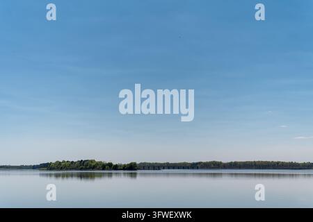 Blick auf einen ruhigen See mit einer fernen Brücke und üppigen grünen Bäumen entlang des Ufers in Camden, Alabama, Vereinigte Staaten. Stockfoto