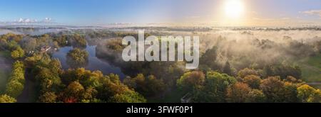 Herbstsonnenaufgang über Heaton Park in Prestwich und Higher Blackley, Manchester, England, tief hängender Morgennebel und lebendiges Herbstlaub umgeben Stockfoto