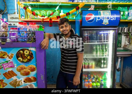 Junger Mann lehnt sich an die Theke eines kleinen Snackbar in der Westprovinz, Negombo, Sri Lanka Stockfoto