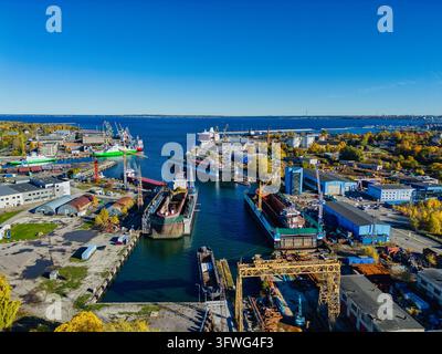 Drohnenaufnahme eines industriellen Schiffbauers mit schwimmenden Trockendocks und Frachtschiffen an einem sonnigen Tag Stockfoto