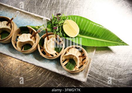 Vier gedämpfte Knödel in Bambuskörben mit Limette und Microgreens Stockfoto