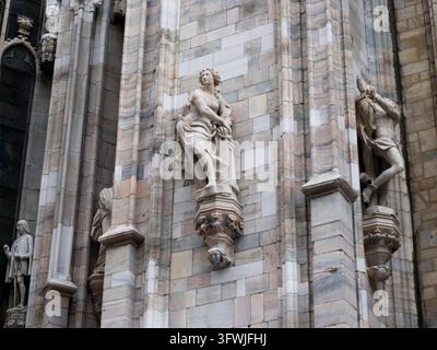 Mailand, Italien – 2. März 2026: Marmorstatuen stehen auf geschnitzten Konsolen entlang der verwitterten Steinmauer des Mailänder Doms Duomo, ein genauer Blick auf seinen Reichtum Stockfoto