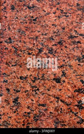 Die Textur des roten Granitbrokens. Hintergrundbild von rotem Granit. Vertikaler abstrakter Hintergrund. Stockfoto