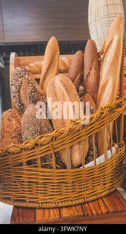 verschiedene frische Brotsorten, Baguettes und Brote mit Samen in einem rustikalen Weidenkorb präsentiert Stockfoto